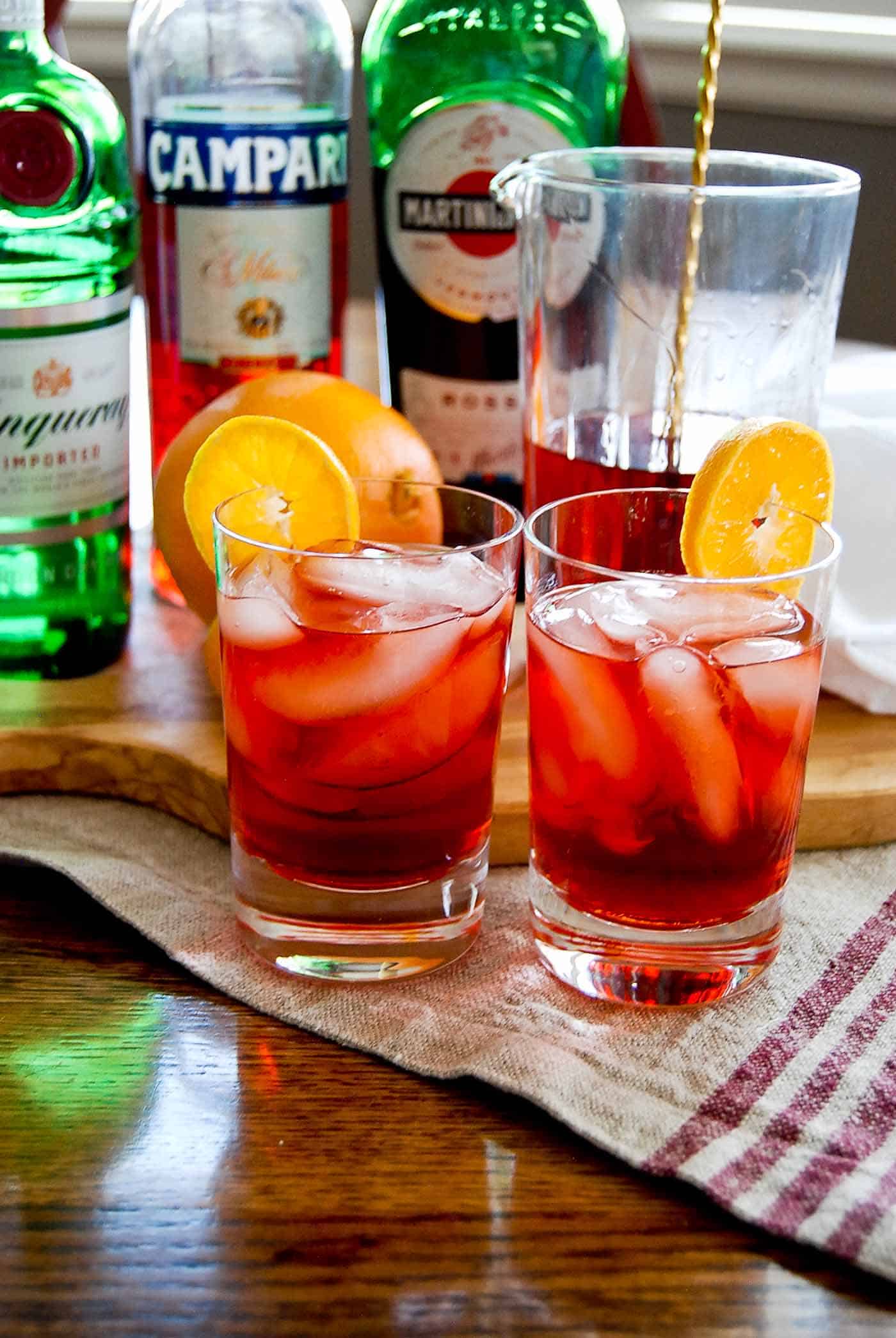 negronis in glasses garnished with orange slices.