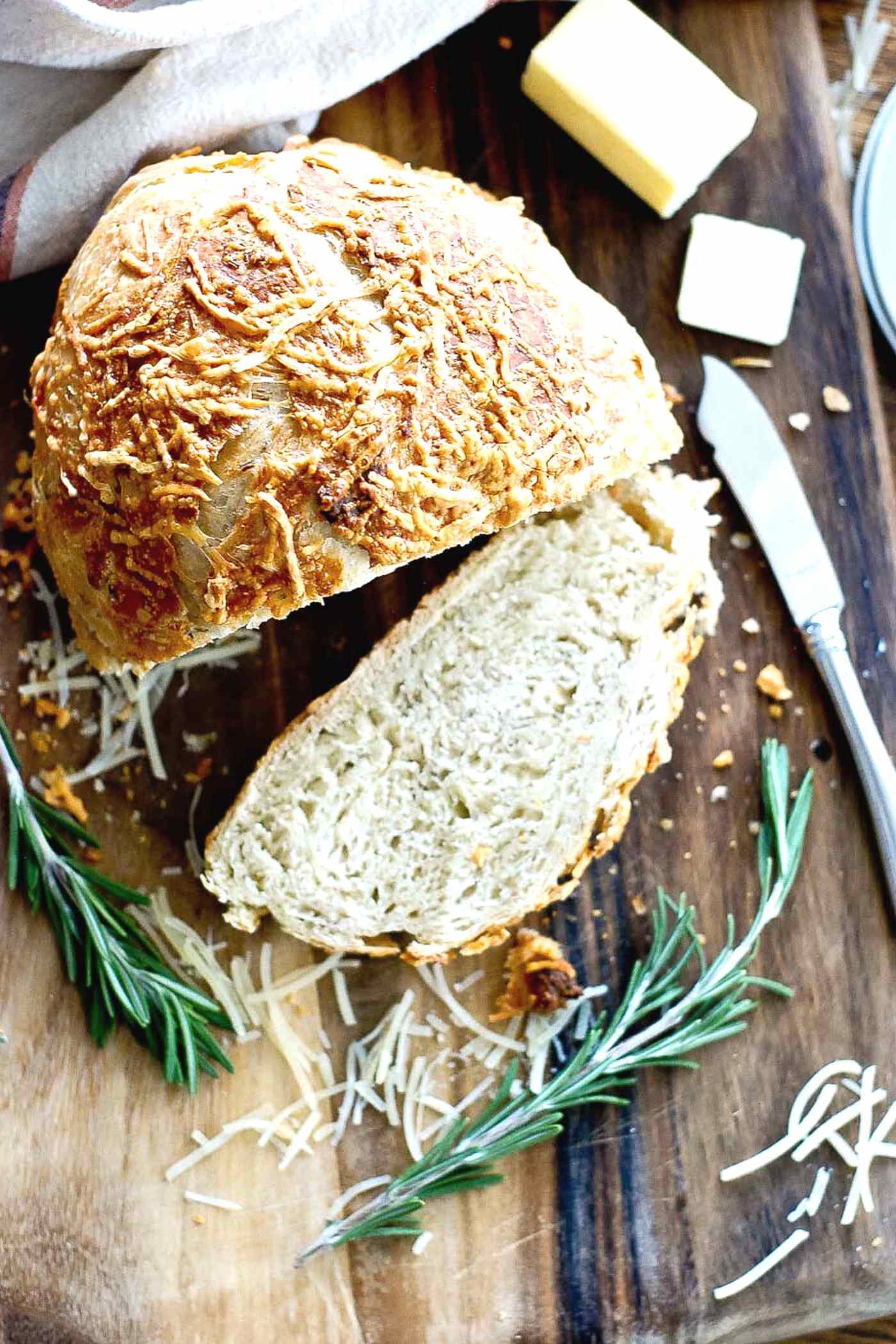 freshly baked rosemary parmesan bread, sliced on a cutting board.