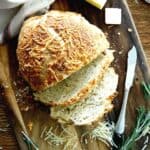 freshly baked rosemary parmesan bread, sliced on a cutting board.