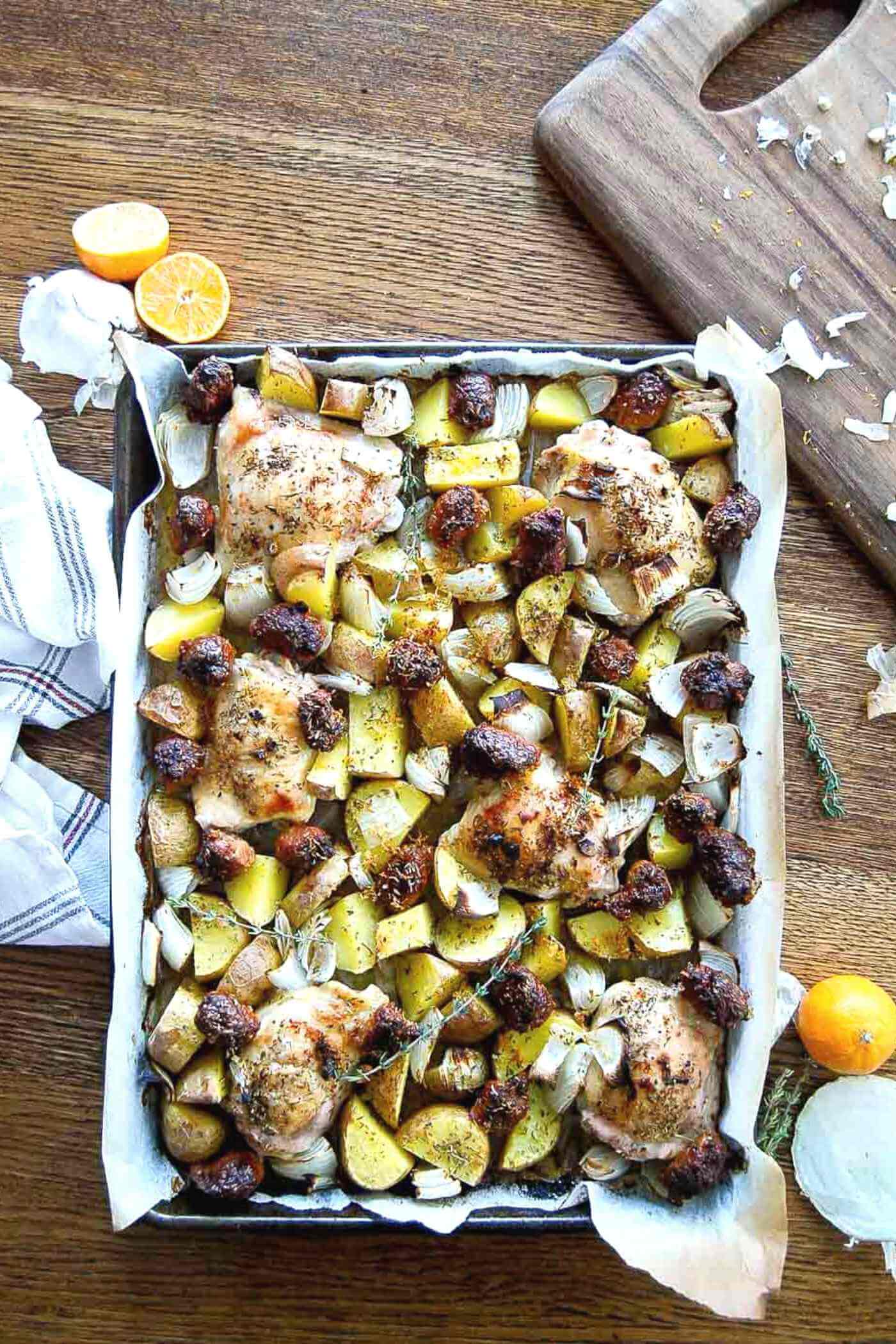 sheet pan chicken thighs with sausage, potatoes and onions.