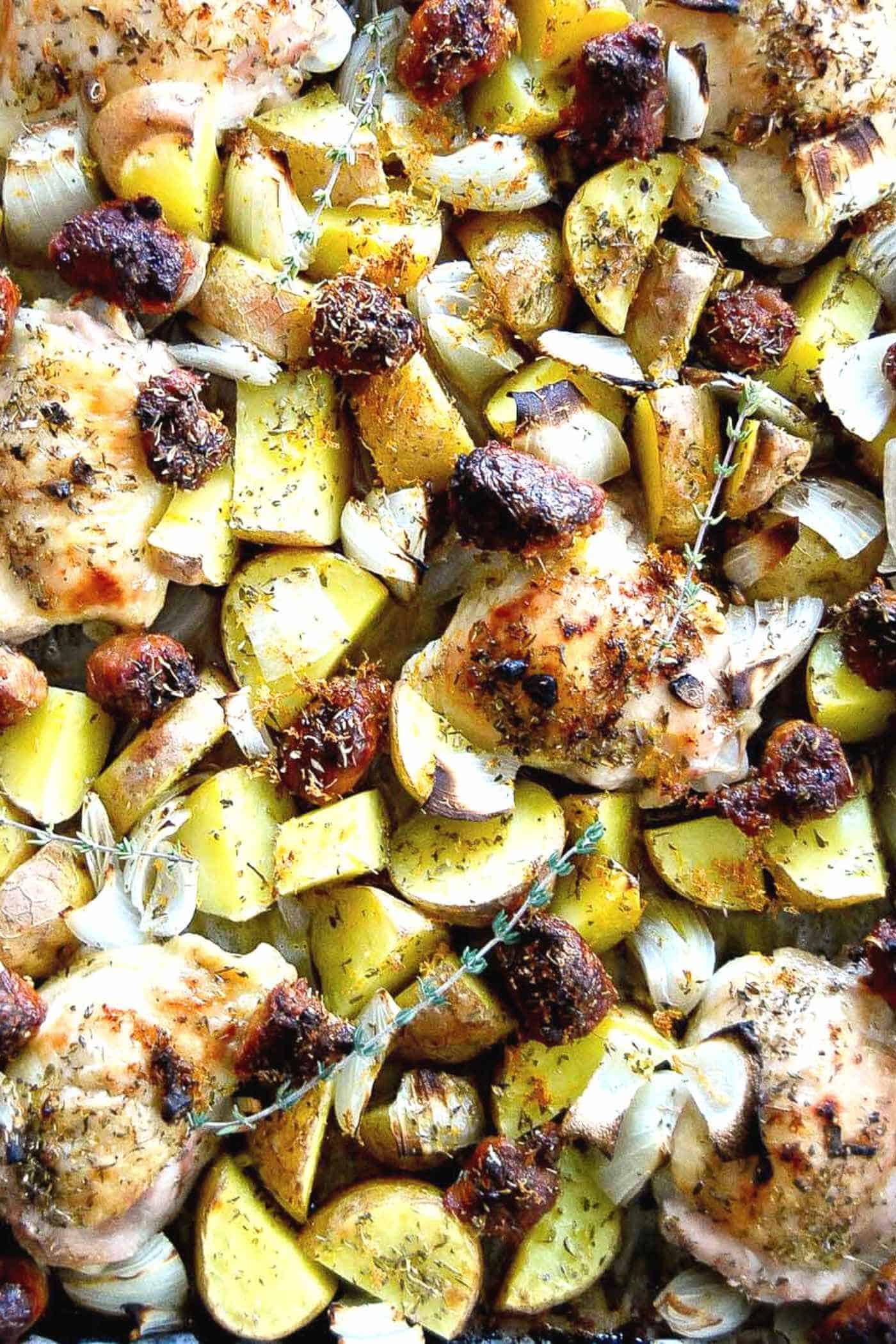 sheet pan chicken thighs with sausage, potatoes and onions.