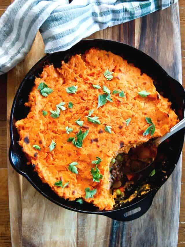 baked sweet potato shepherds pie in skillet with one serving spooned out.