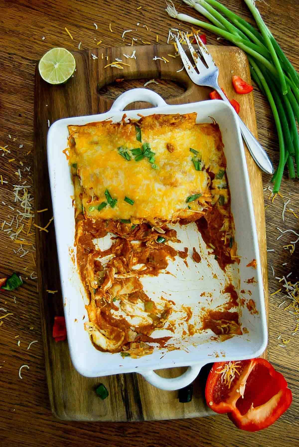 chicken enchiladas with red enchilada sauce in pan.