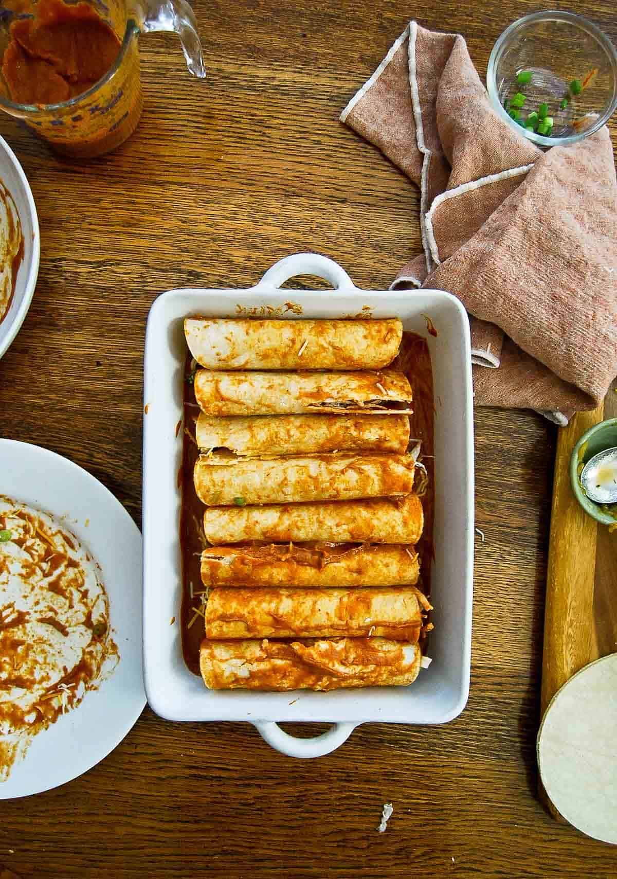 red chicken enchiladas assembled in baking dish.