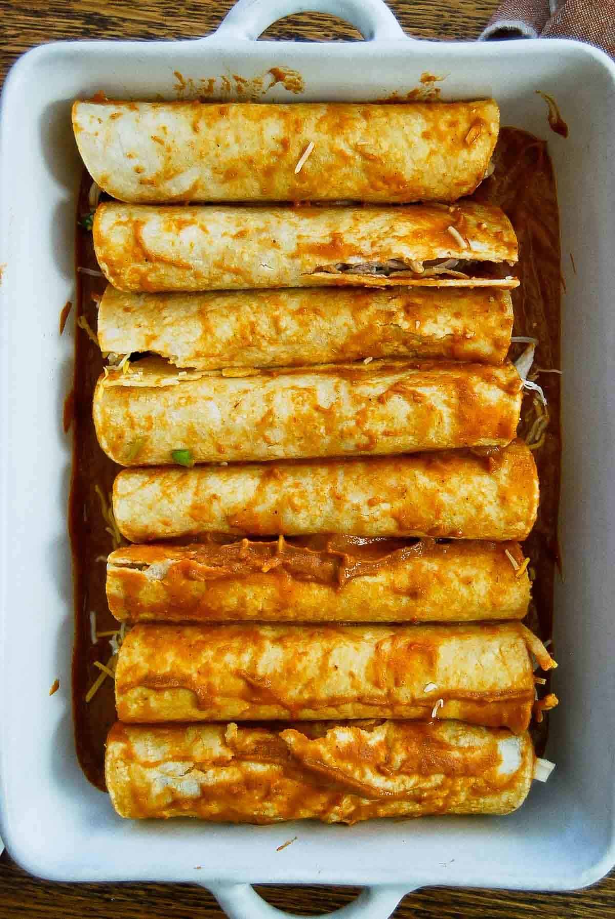 red chicken enchiladas assembled in baking dish - close up.