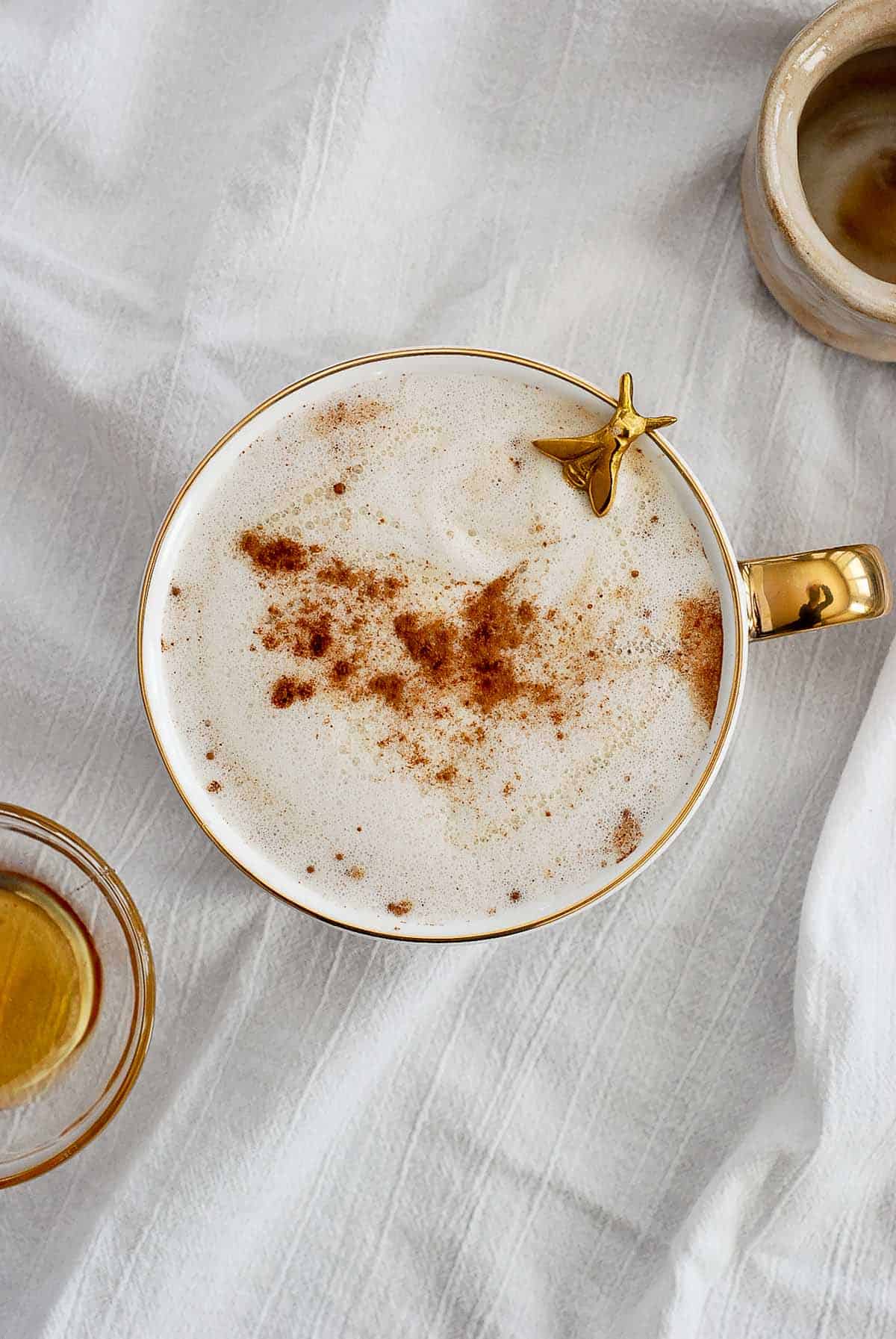 honey oatmilk latte in mug with spoon peeking out.