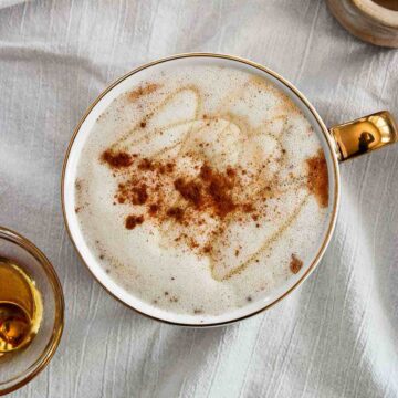 Honey Oatmilk Latte With Cinnamon sprinkled on top in mug.