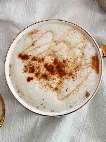 Honey Oatmilk Latte With Cinnamon sprinkled on top in mug.