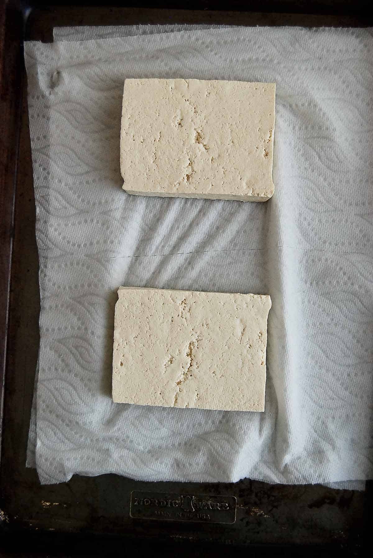 blocks of tofu on paper towel lined baking sheet.