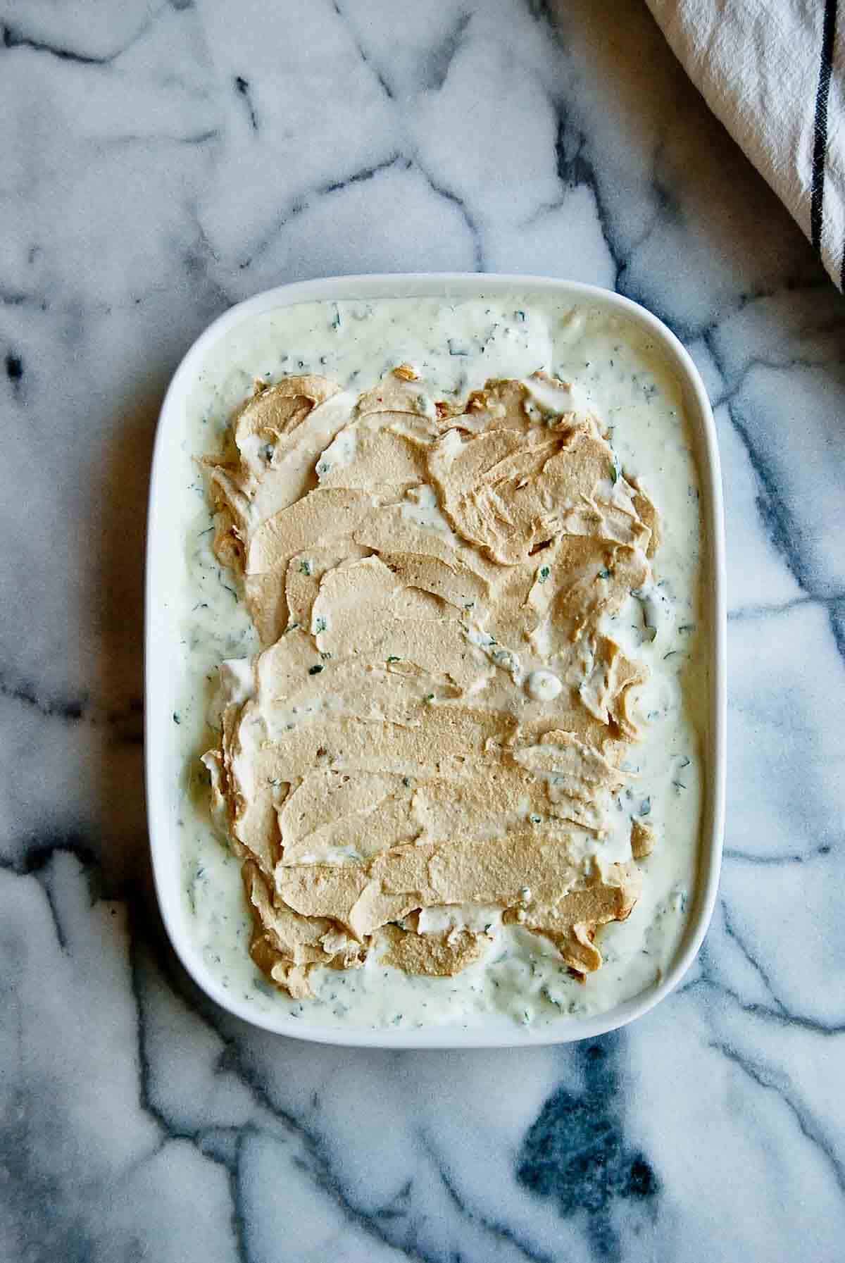 greek yogurt dip with hummus spread on top on platter.