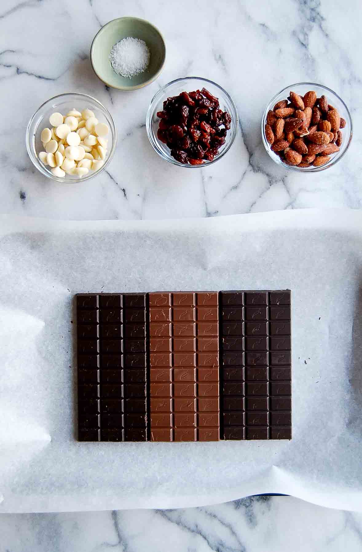 chocolate bars on baking sheet with toppings in bowls.