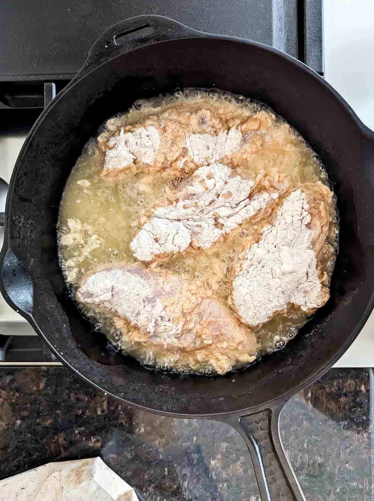 chicken frying in pan.