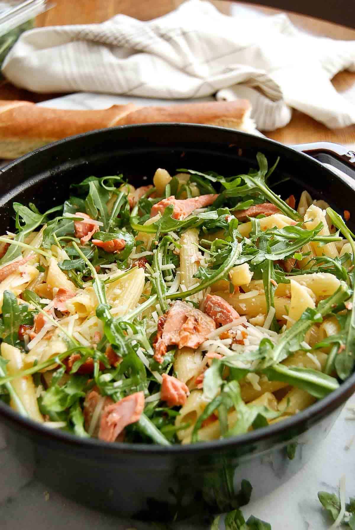 side angle of lemon salmon pasta with loaf of bread in the background.