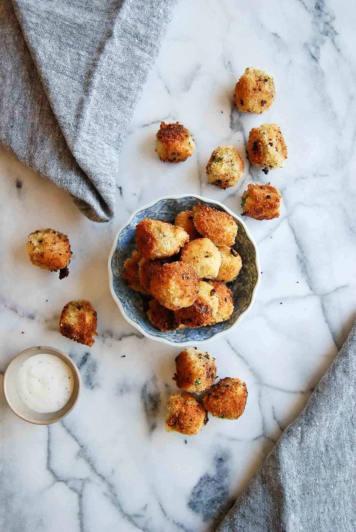 top down view of fried mashed potato balls in bowl and on counter with ranch dressing on the side.