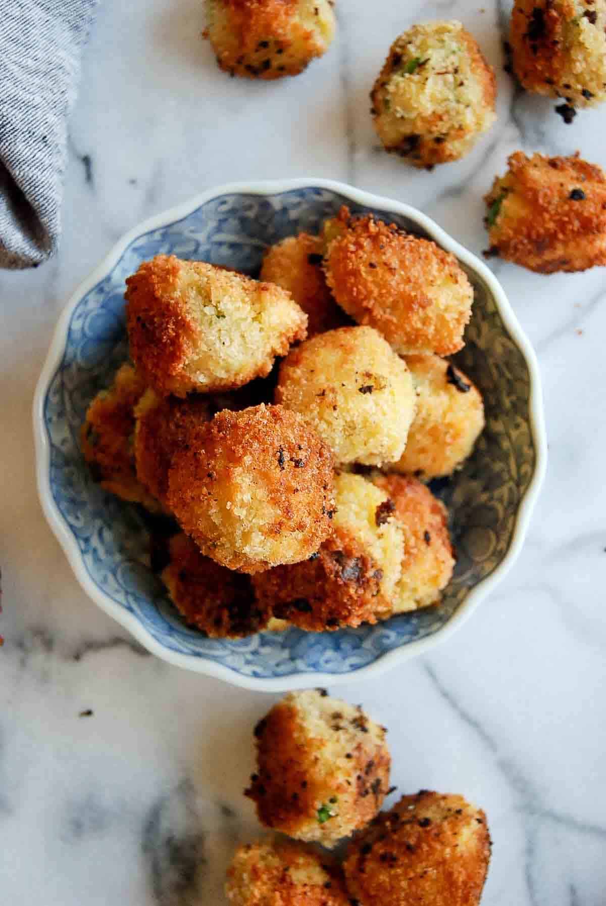 top down view of fried mashed potato balls in bowl.