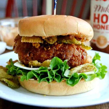 hot honey fried chicken sandwich on plate with pickle chips