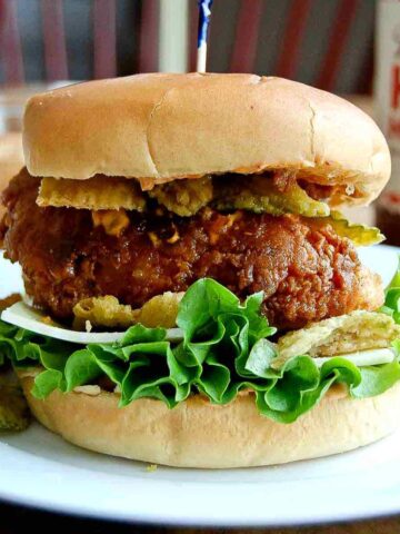 hot honey fried chicken sandwich on plate with pickle chips