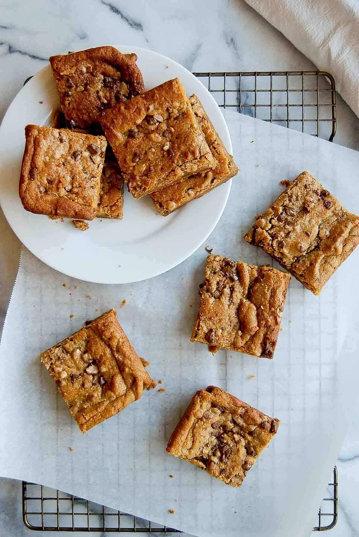 peanut butter blondies cut into squares, arranged on a cooling rack and plate.
