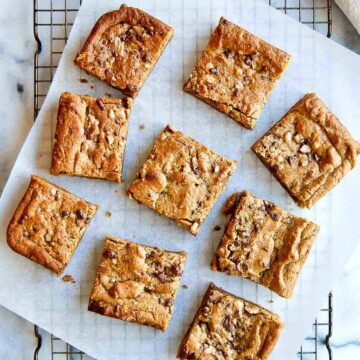 peanut butter blondies on parchment paper and cooling rack, cut into squares.