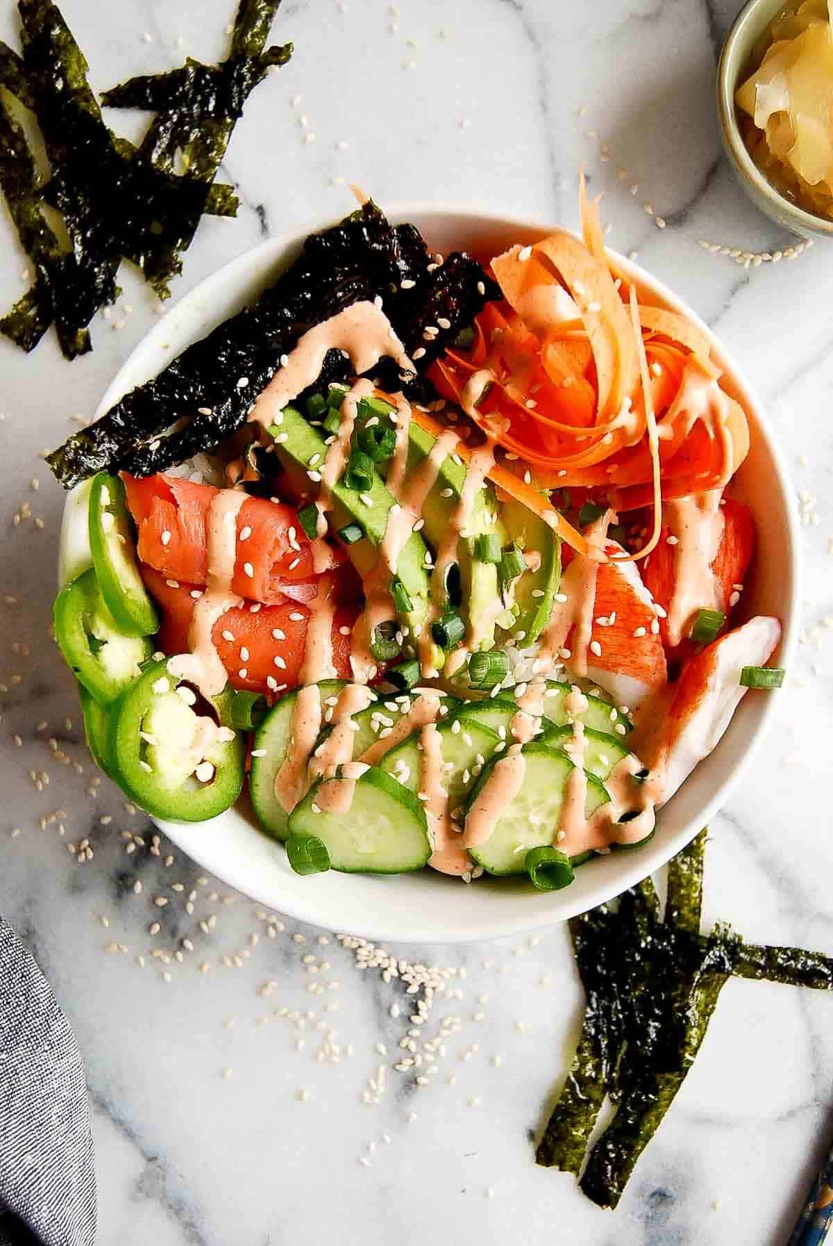 smoked salmon sushi rice bowl with cucumber, carrots, and jalapeno.