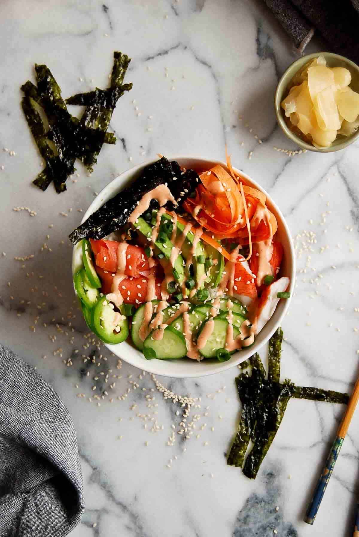 smoked salmon sushi bowl on counter with sriracha mayo drizzled over the top.