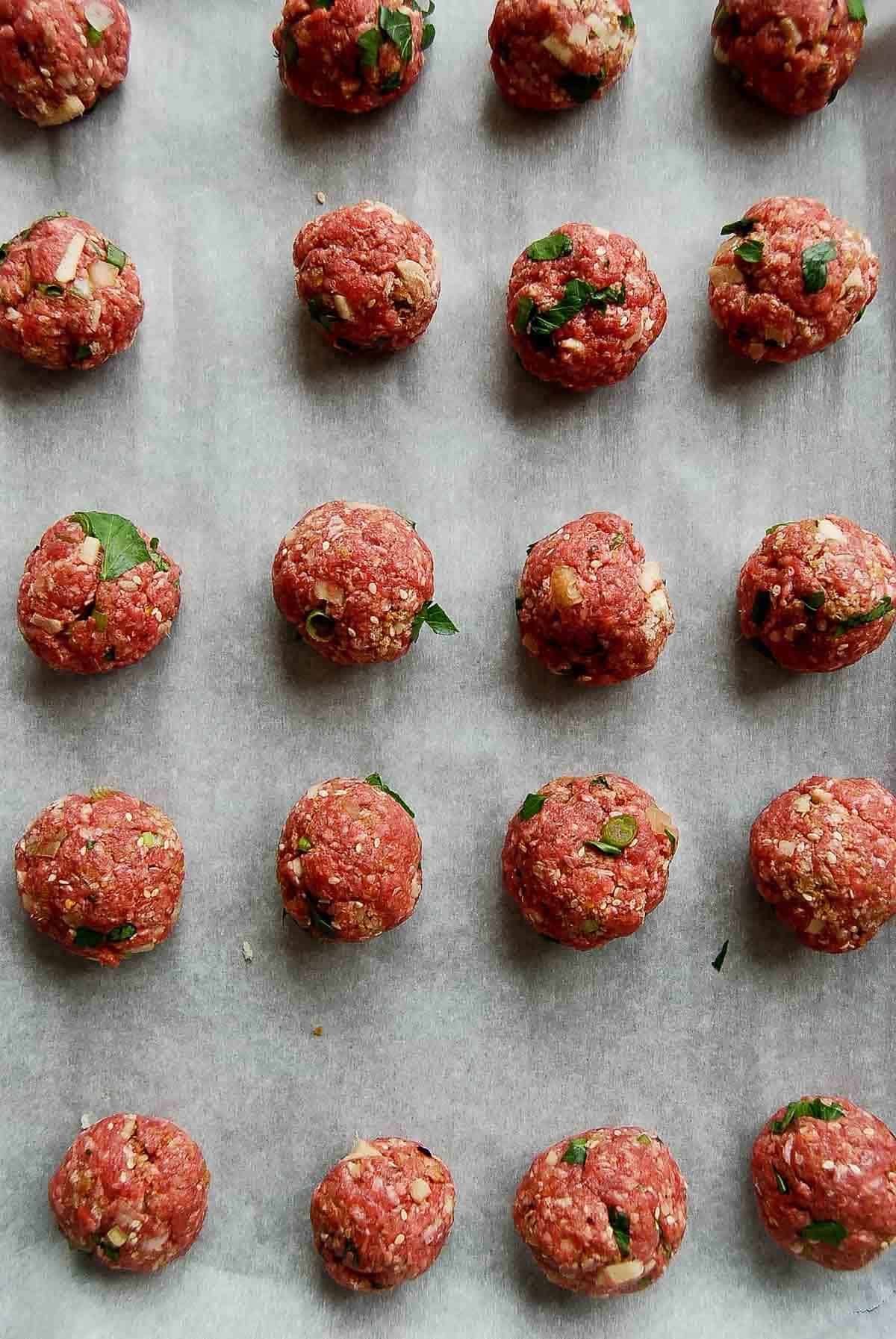 handmade meatballs on baking sheet.