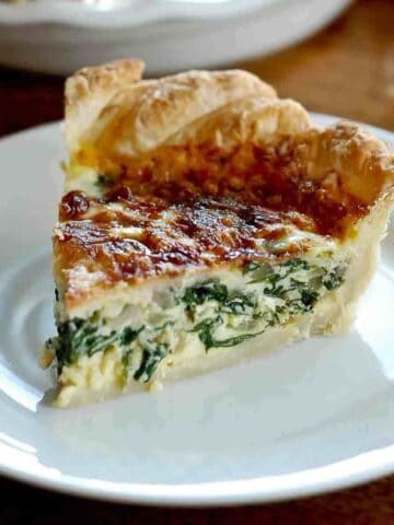 slice of spinach quiche on plate.