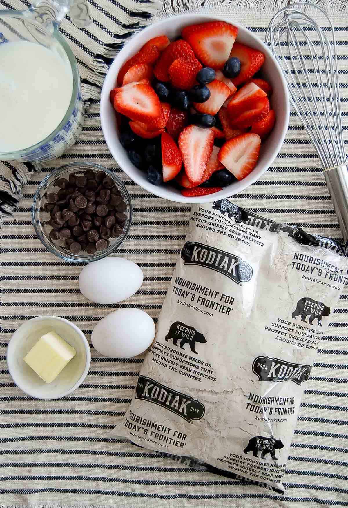 kodiak cake pancake mix and other ingredients for sheet pan pancakes on placemat.