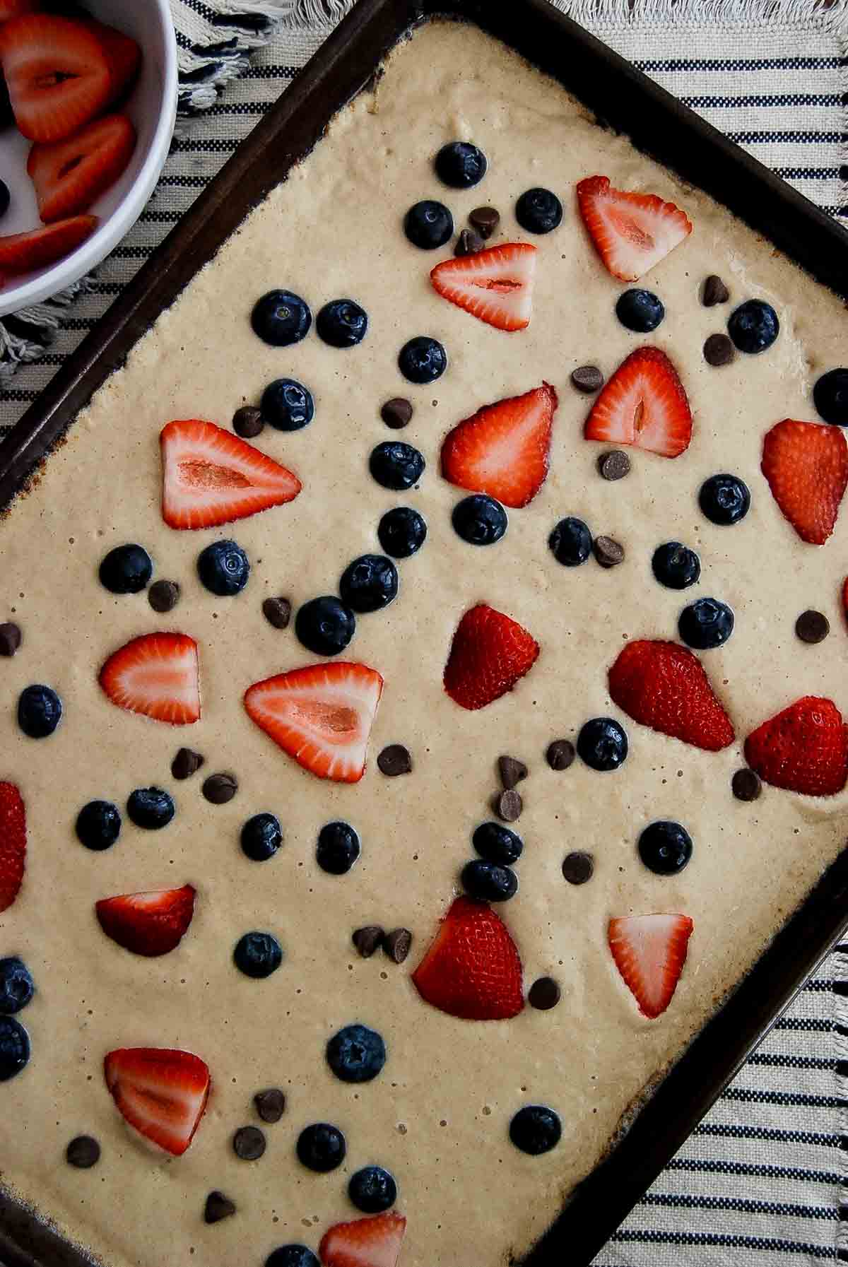 close up of sheet pan with pancake batter and toppings.