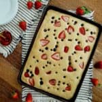 sheet pan pancakes with mix in pan with strawberries, blueberries and chocolate chips.