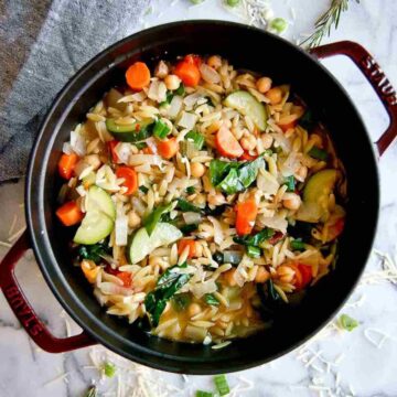 chickpea stew with orzo and greens in a pot.
