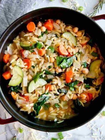 chickpea stew with orzo and greens in a pot.