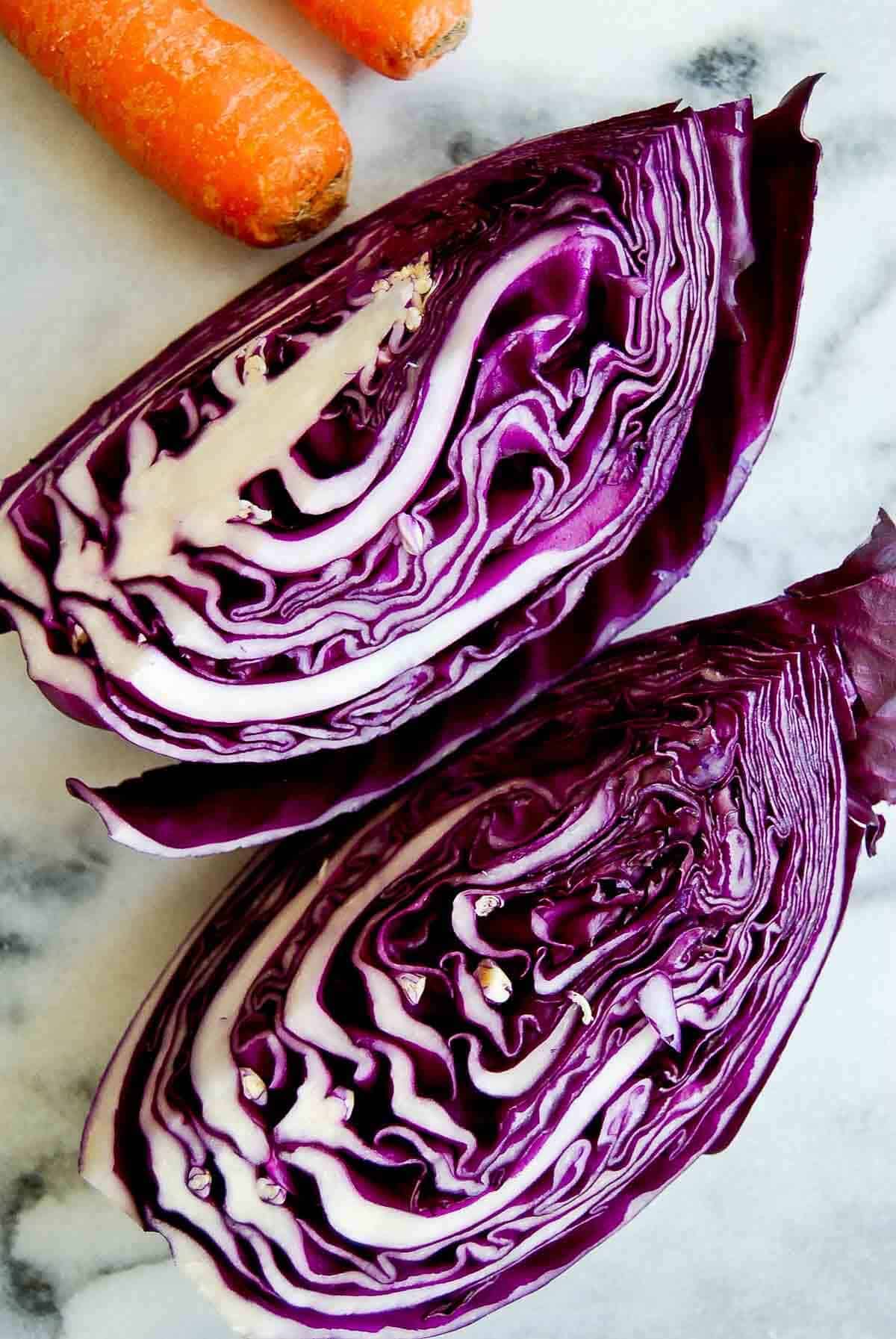 2 quarter red cabbages on cutting board.