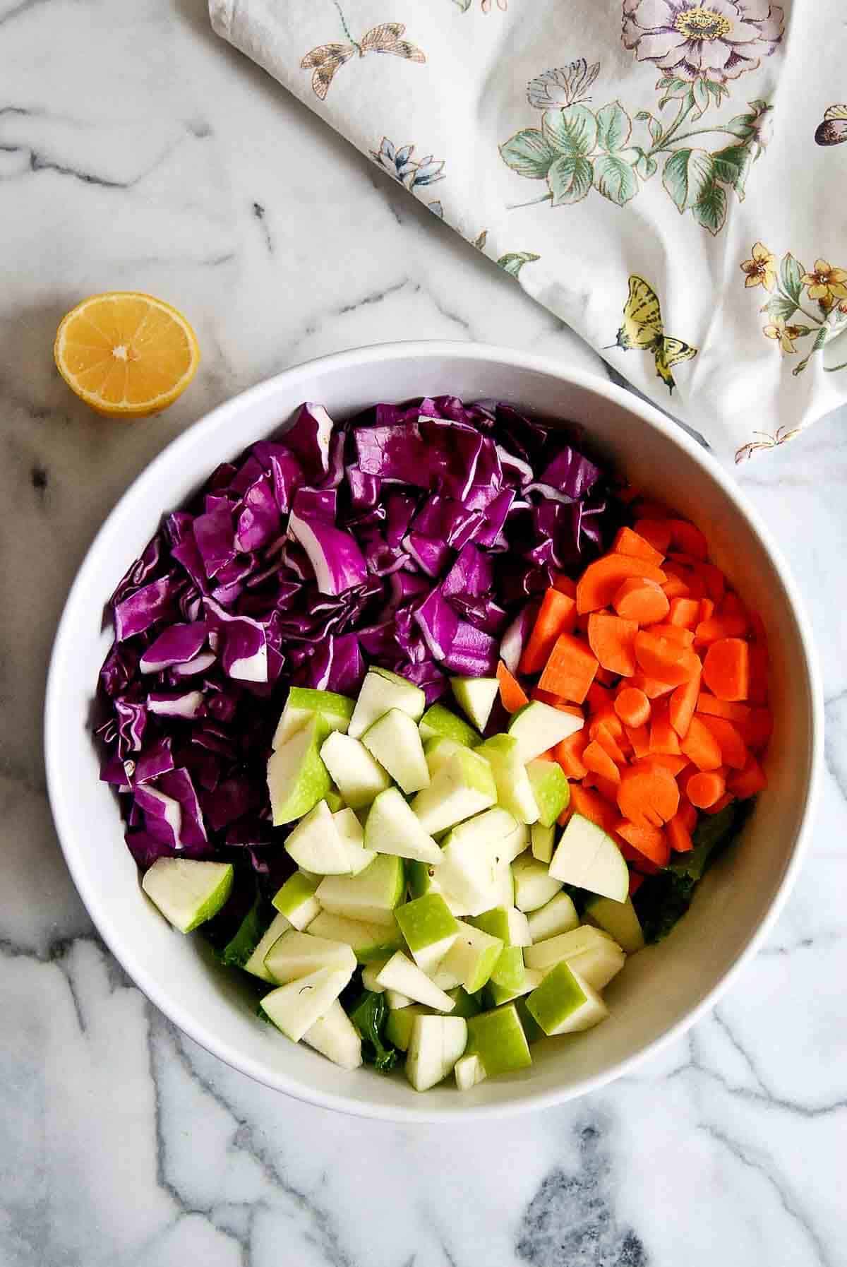 carrots, red cabbage and granny smith apples, chopped, in bowl.