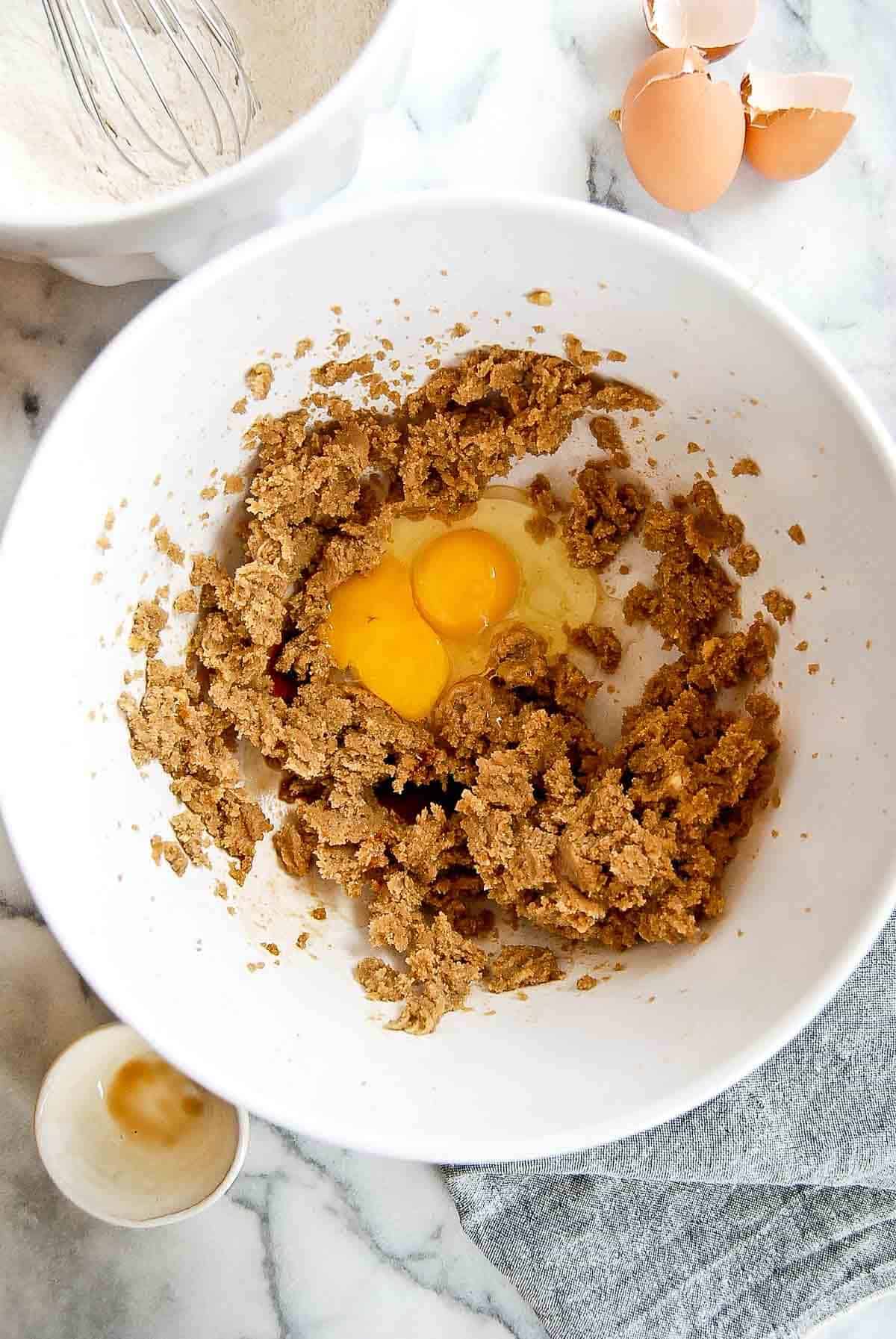 butter and sugars in bowl with egg and egg yolk.