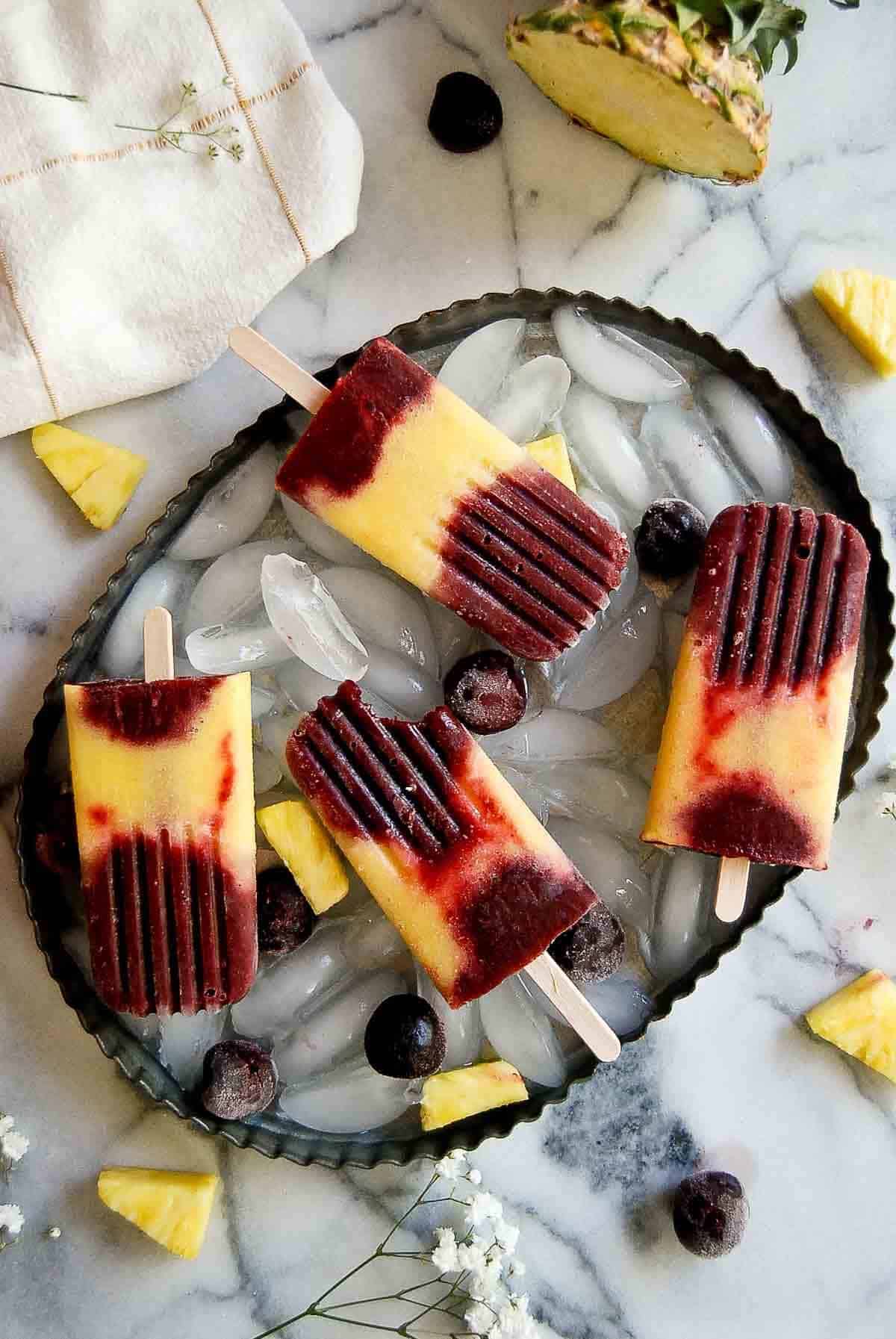 red and yellow fruit popsicles on tray with ice.