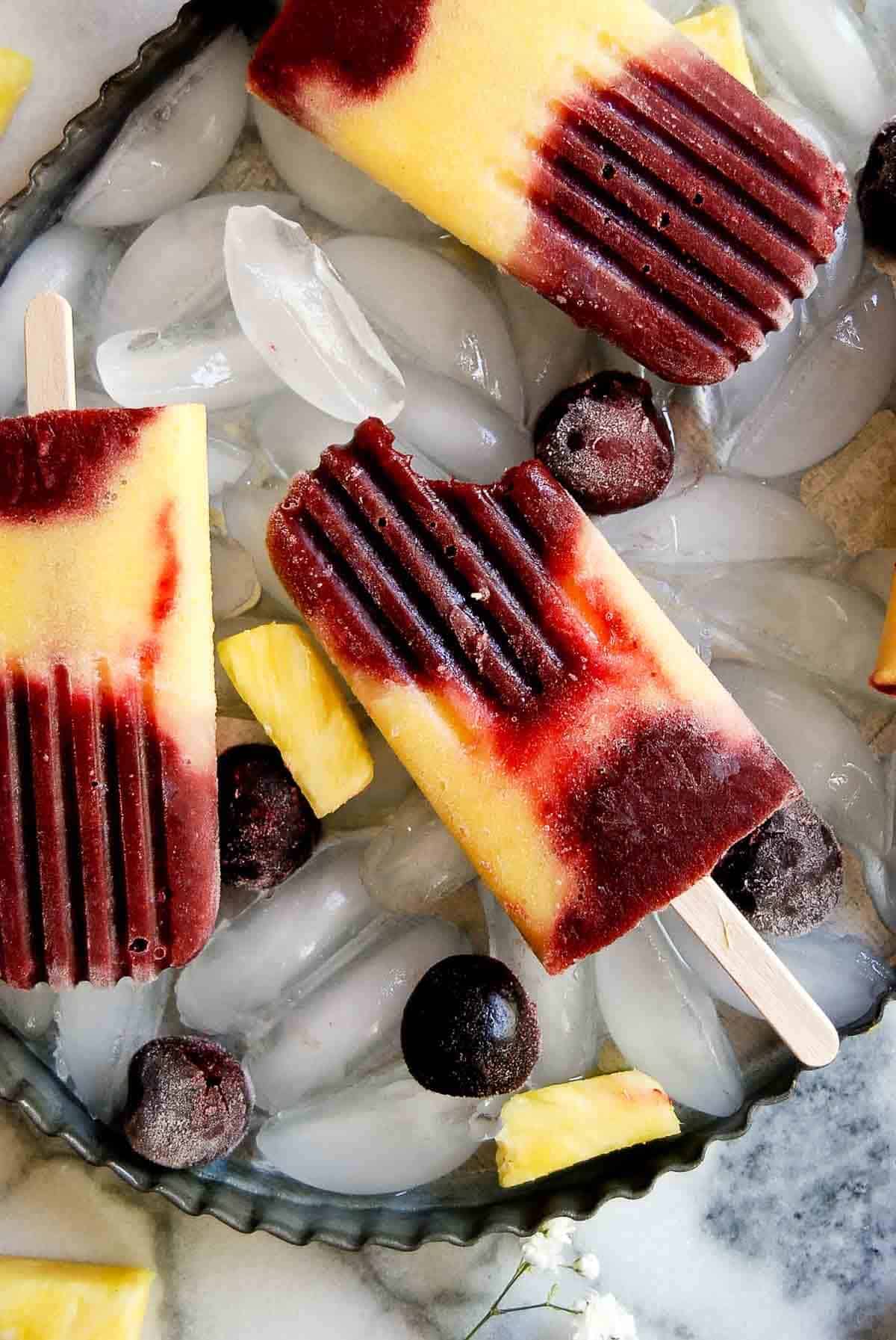 homemade cherry pineapple popsicle with bite taken out of it.