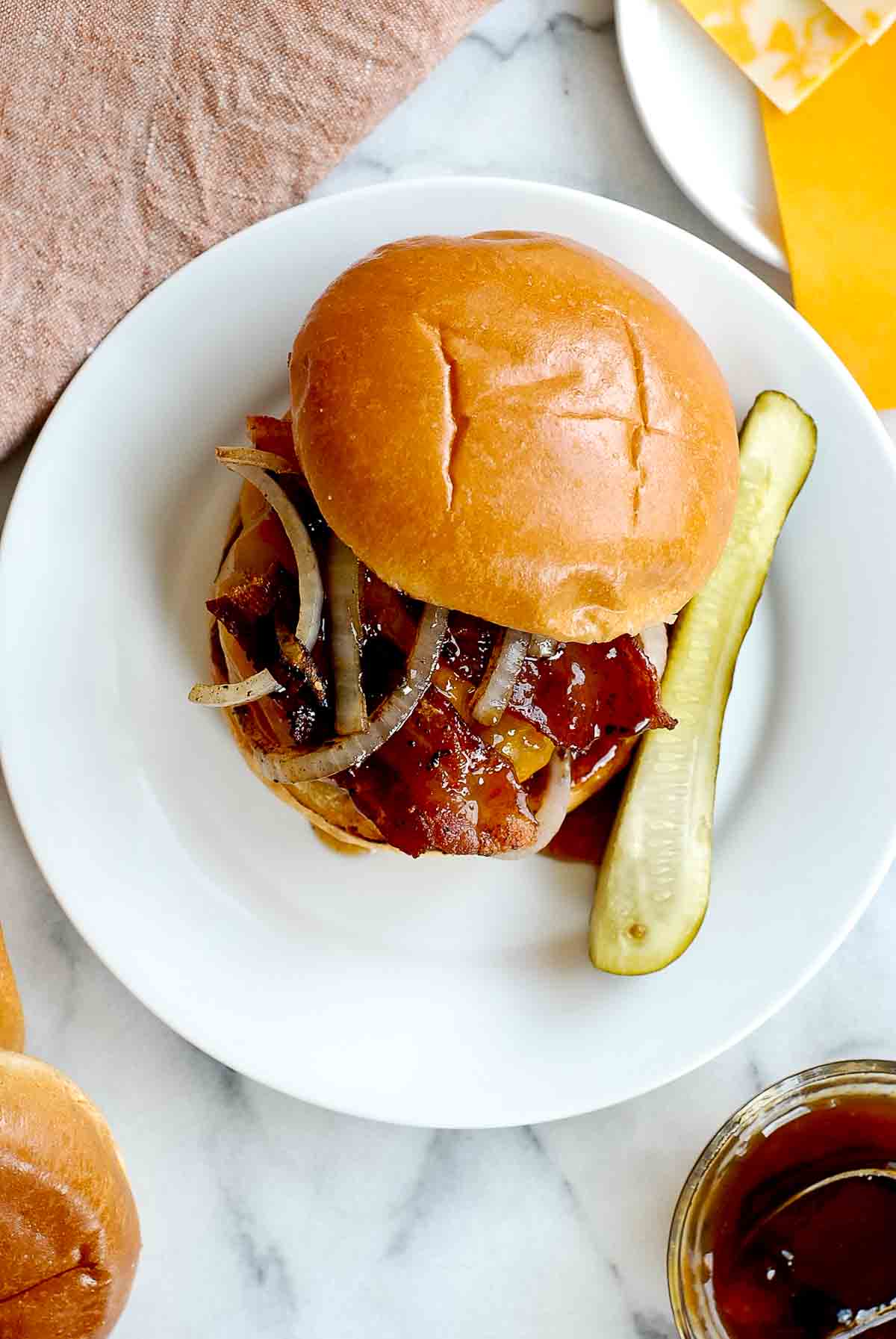 top down view of spicy bacon burger from whataburger on plate with pickle.