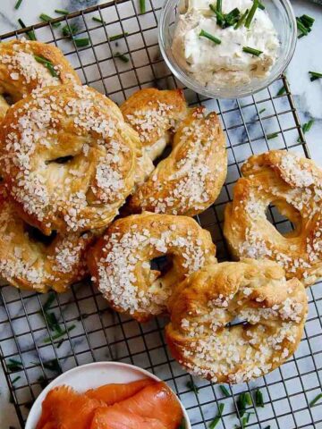 Salt bagels on cooling rack with smoked salmon and cream cheese on the side.