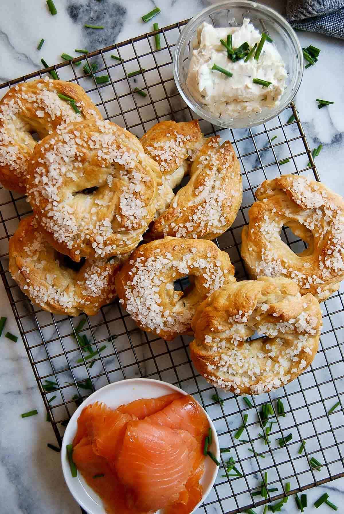 salt bagels on cooling rack with smoked salmon and cream cheese on the side.