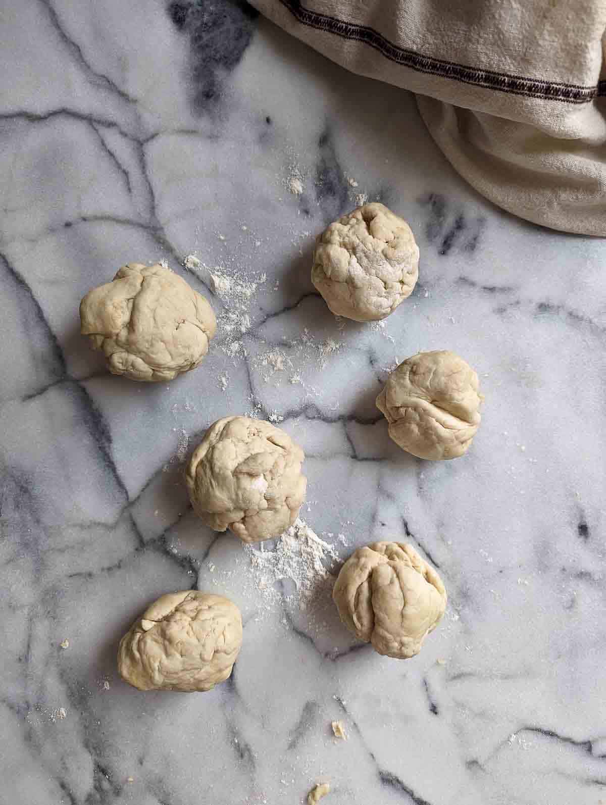balls of dough for bagels on marble cutting board.