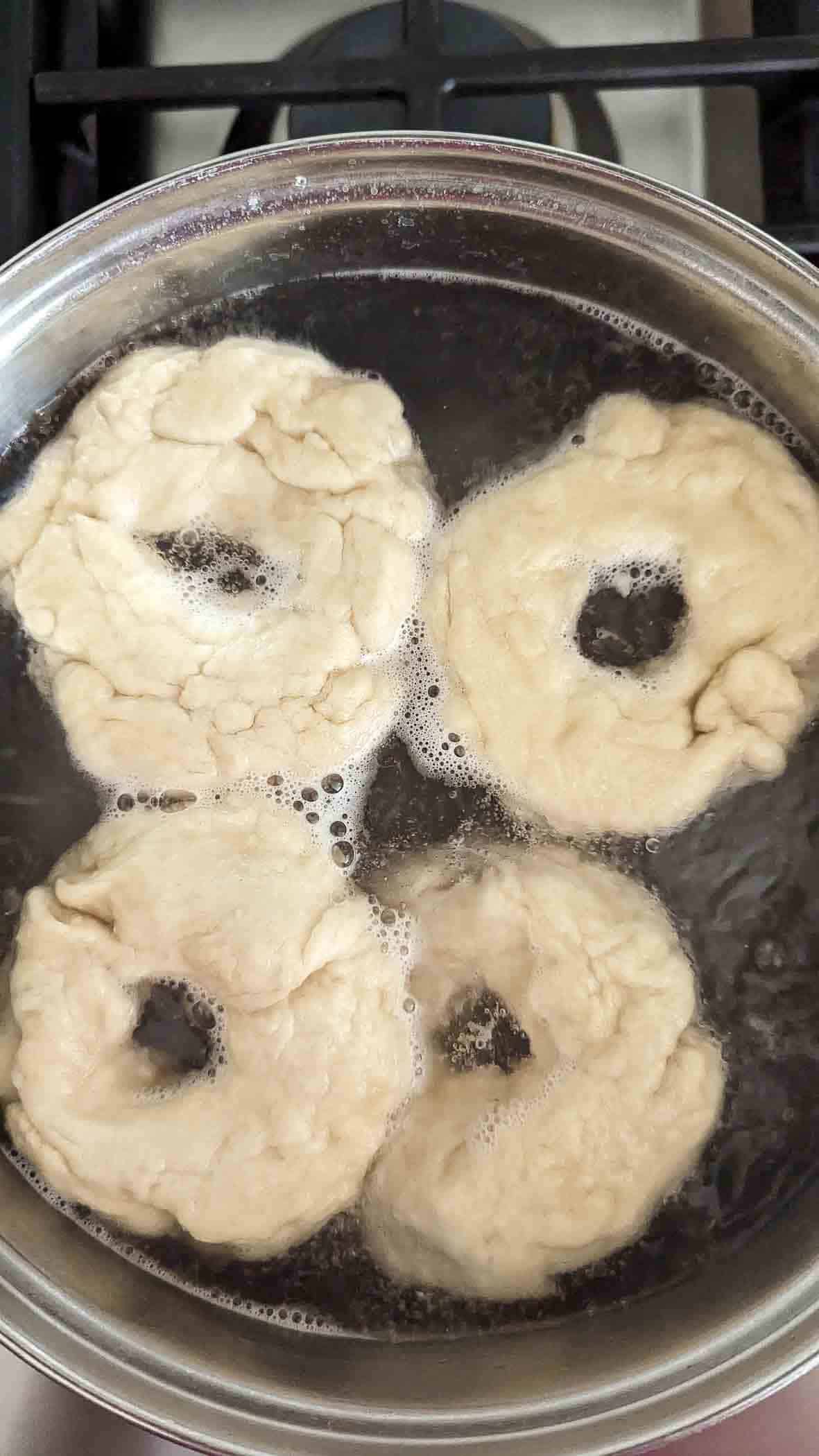 bagel rings boiling in baking soda water.