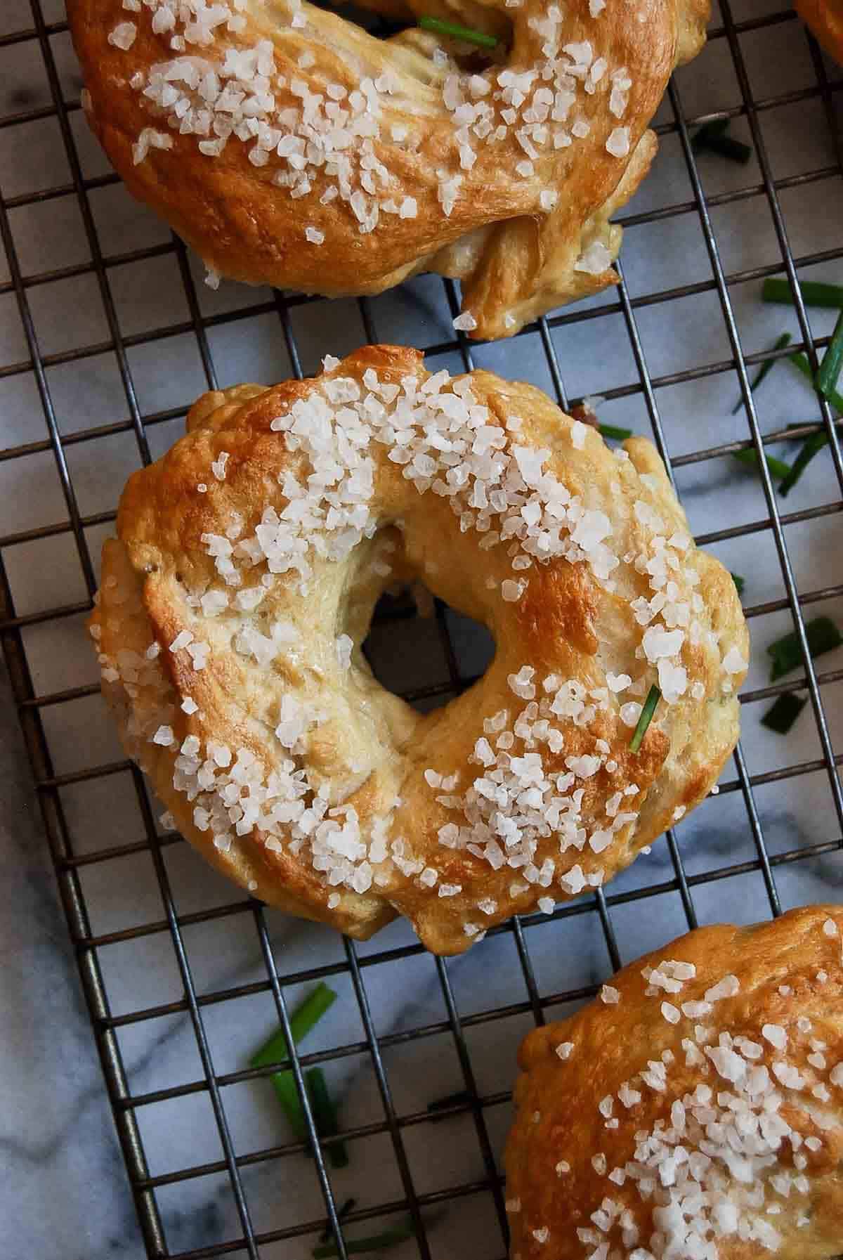 close up of salt bagel on cooling rack.