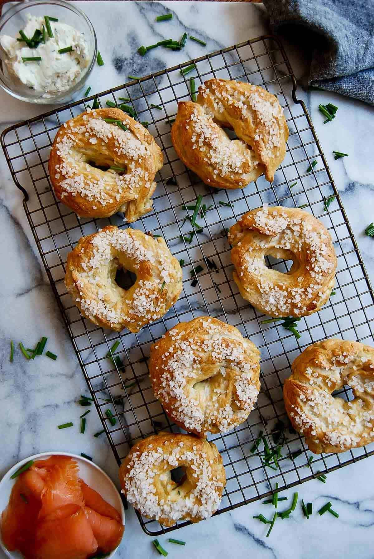 salt bagels on cooling rack with smoked salmon and cream cheese on the side.