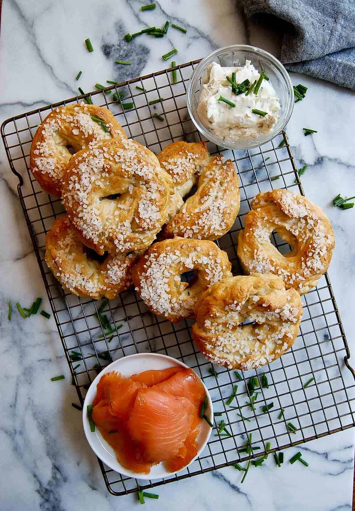 salt bagels on cooling rack with smoked salmon and cream on the side.