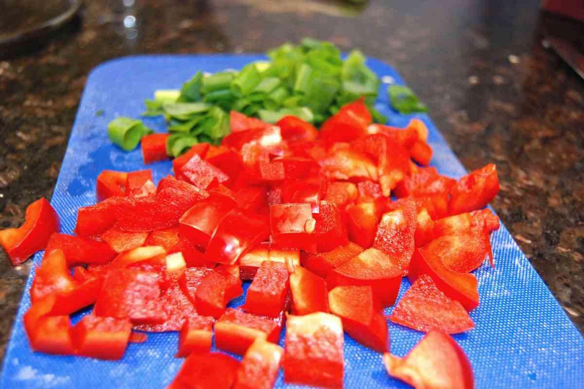 chopped red pepper and scallions on cutting board to use in huevos con chorizo y papas.