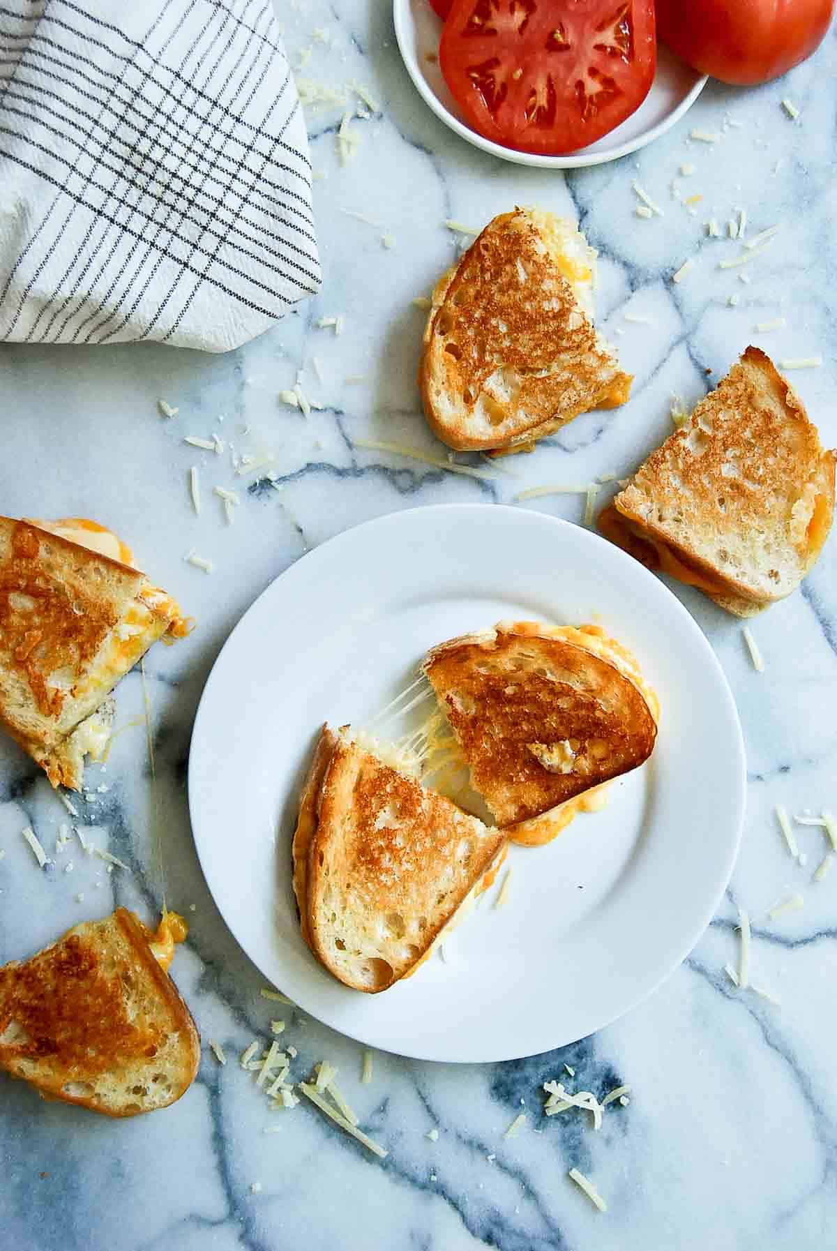 sourdough grilled cheese sandwiches, cut in half with cheese stretching across.