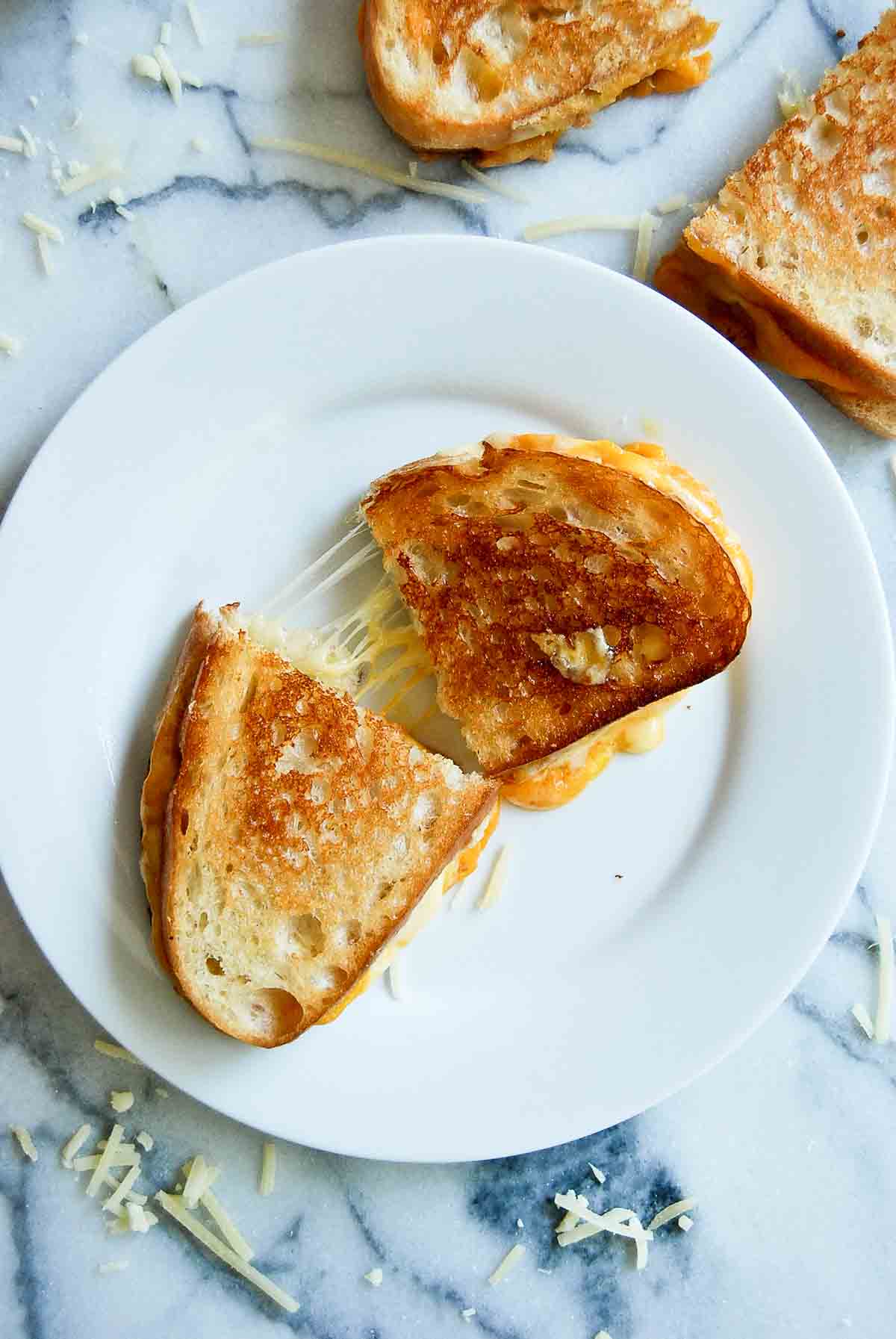 closeup of a sourdough grilled cheese sandwich cut in half with melted cheese.