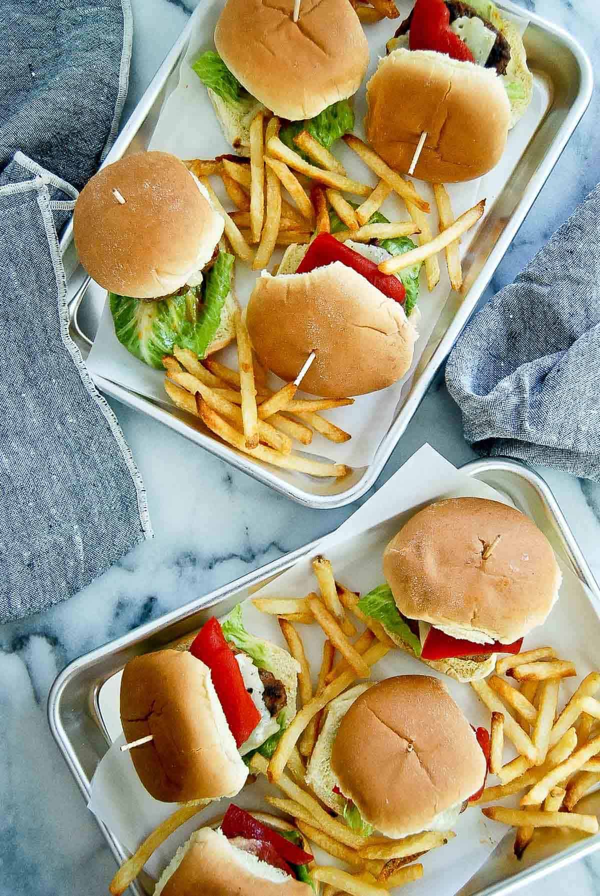 2 trays filled with spanish sliders and french fries.