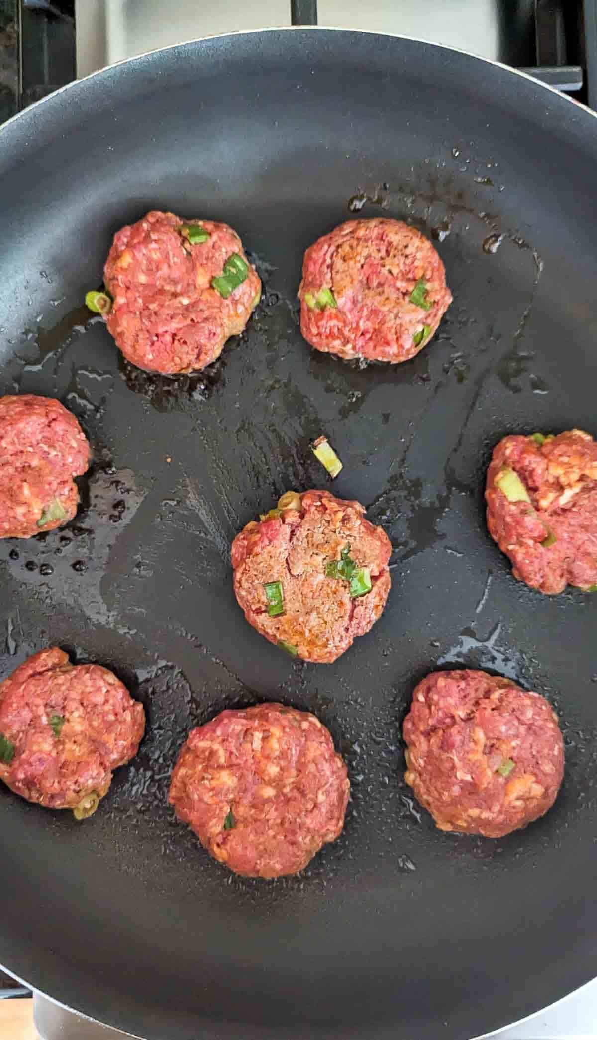 chorizo sliders cooking on skillet.